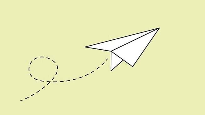 Weißer Papierflieger auf hellgrünem Hintergrund