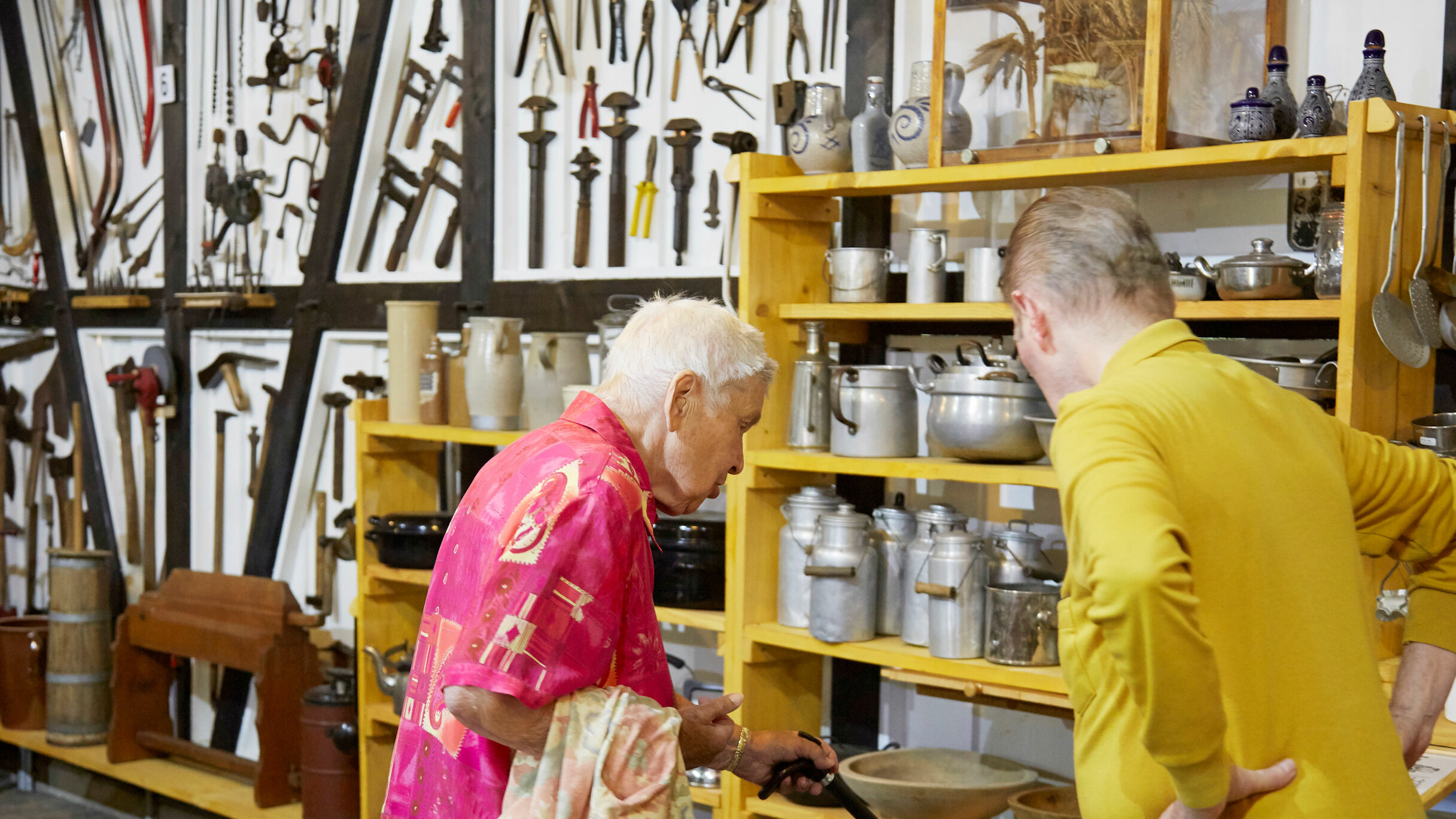 Auf dem Foto schauen sich zwei Senioren eine Ausstellung von alten Töpfen an