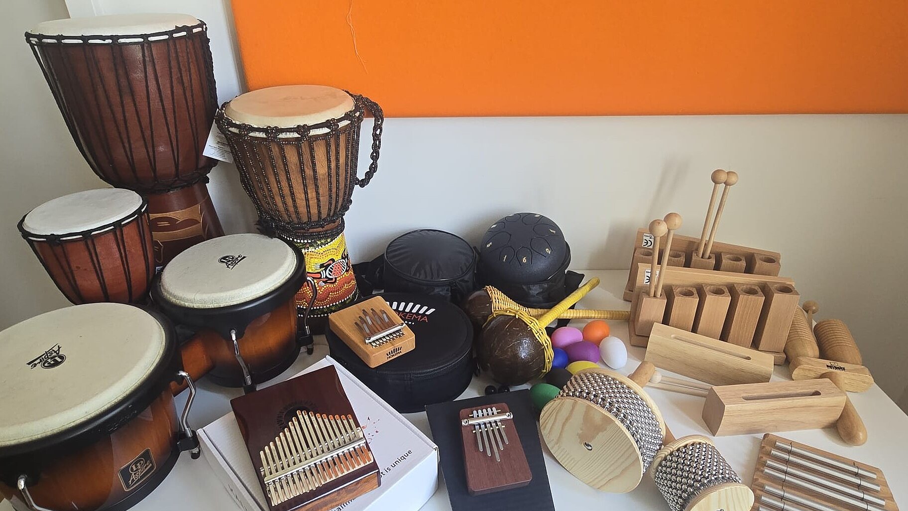 Foto: Auf einem Tisch stehen verschiedene Rhythmus-Instrumente, u.a. Kalimba, Tongue Drum, Rasseln, Bongos und Djembe