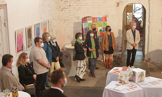 Vernissage zur Ausstellung "broken crayons still color – Die Kunst des Erinnerns", Oktober 2021 | © Bürgerhafen Greifswald Innenraum einer Kirche, in der eine Gruppe von Menschen steht. An den Wänden hängen Kunstwerke