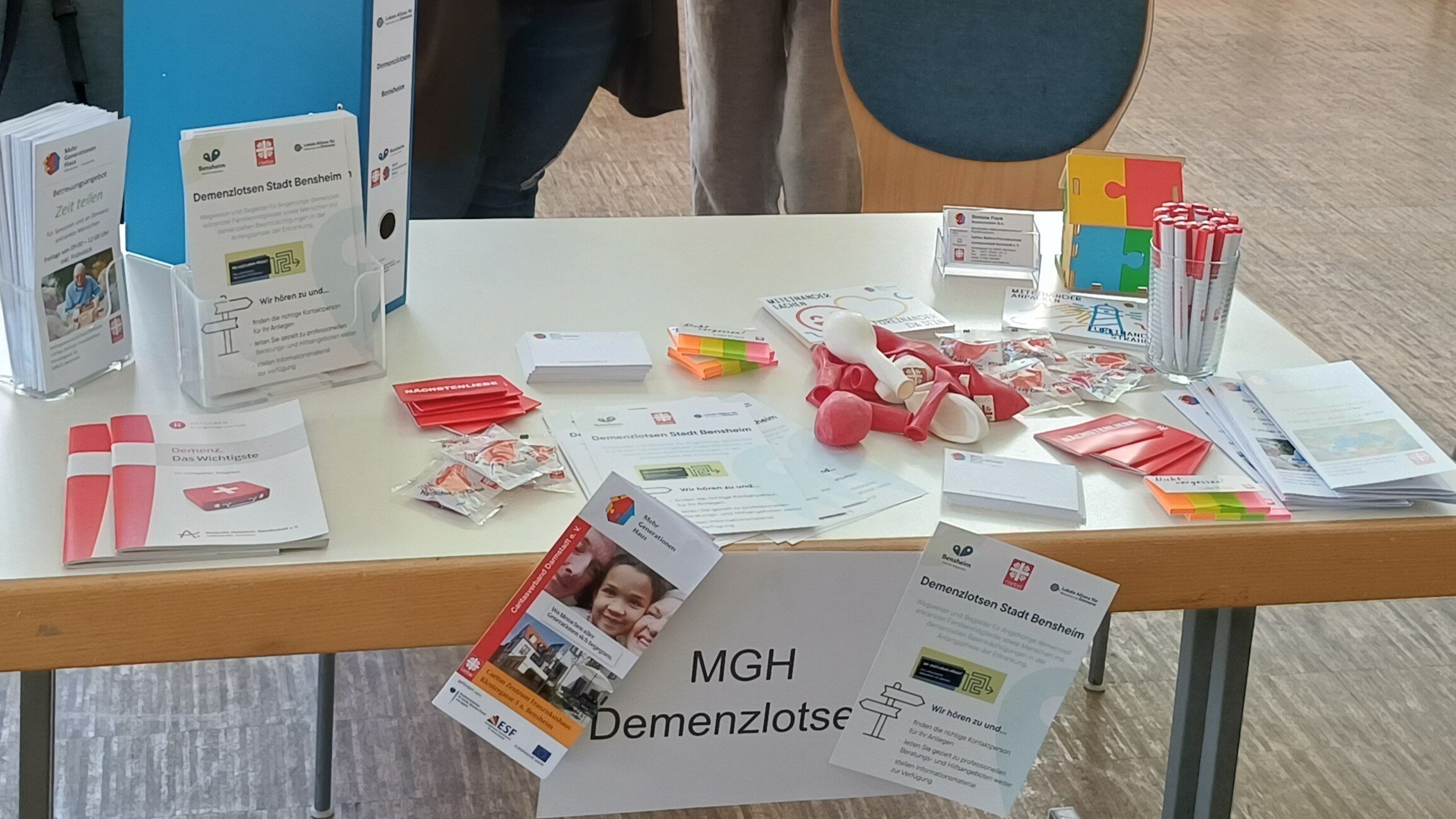 Foto: Ein Tisch, auf dem Flyer, Luftballons, Stifte und anderes Werbematerial liegen.