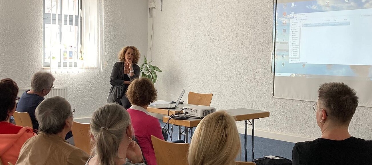Foto: Simone Grecki-Runde hält vor einer Gruppe einen Vortrag