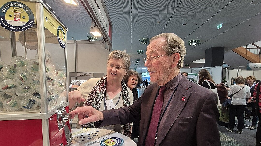 © BAGSO | Hülsmann Brigitte Kuss von der Netzwerkstelle und Franz Müntefering stehen am Kaugummiautomaten