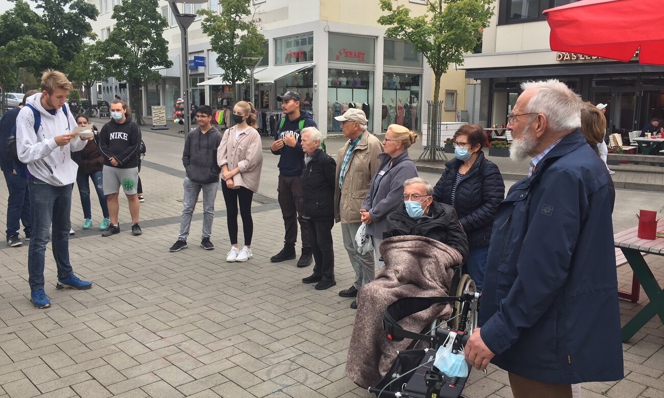 Ältere Menschen, Schülerinnen und Schüler hören Schülervortrag