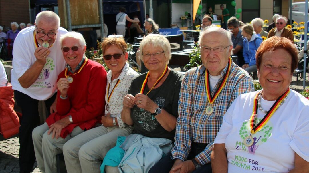 Auf diesem Foto sieht man eine kleine Gruppe älterer Menschen. Alle haben eine Medaille um den Hals. 