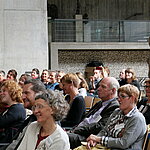 Blick ins Publikum: Die Teilnehmenden sitzen in Stuhlreihen