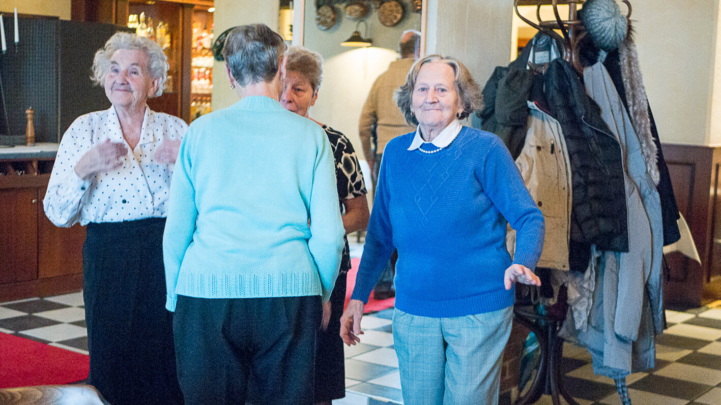 Foto: Vier ältere Damen stehen im Kreis. Davon schauen zwei Damen in die Kamera. Die anderen beiden unterhalten sich. 