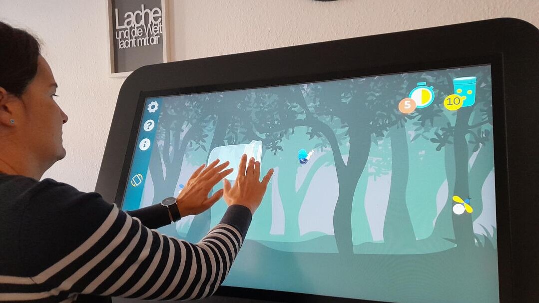 Eine Frau spielt an einem großen Bildschirm