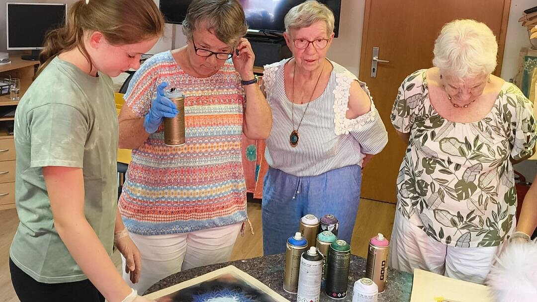 Foto: Seniorinnen und Schülerinnen stehen um einen Tisch mit Bastelmaterial
