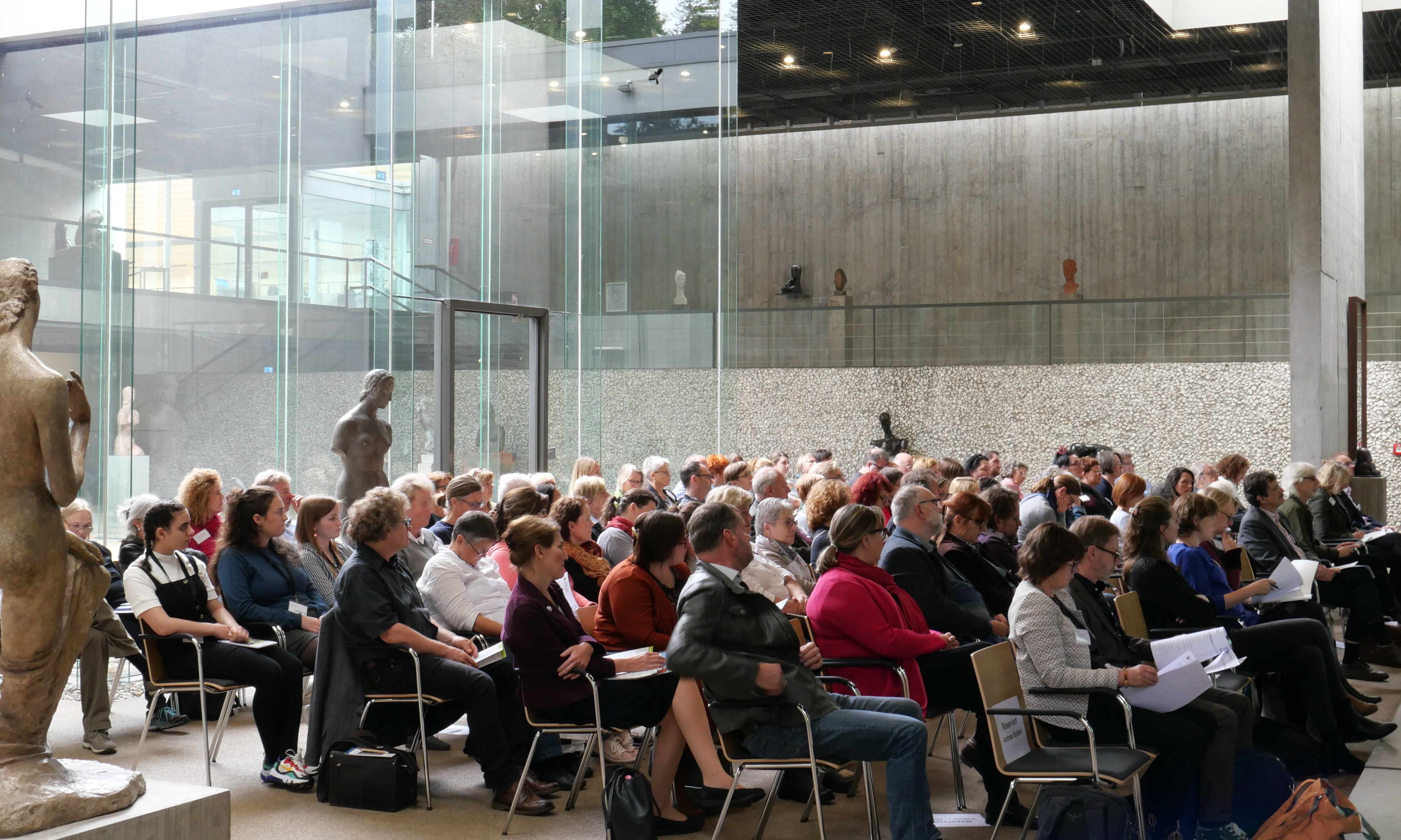 Blick ins Publikum: Die Teilnehmenden sitzen in Stuhlreihen