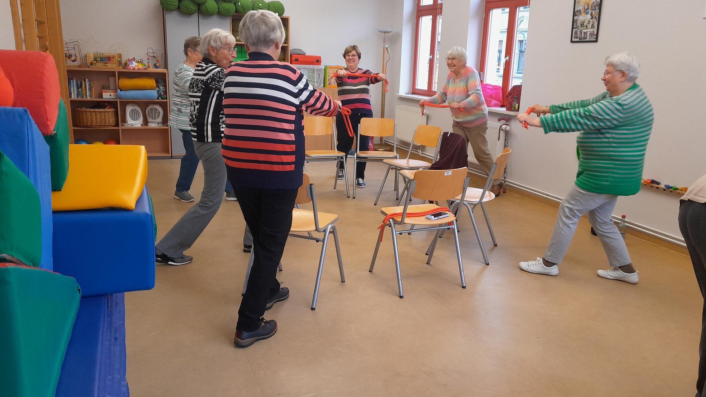 Seniorinnen führen Gymnastikübungen in einem Stuhlkreis aus