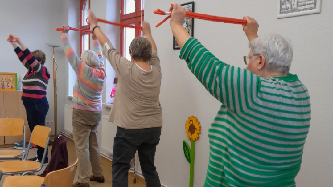 Seniorinnen bewegen sich mit Gymnastikbändern