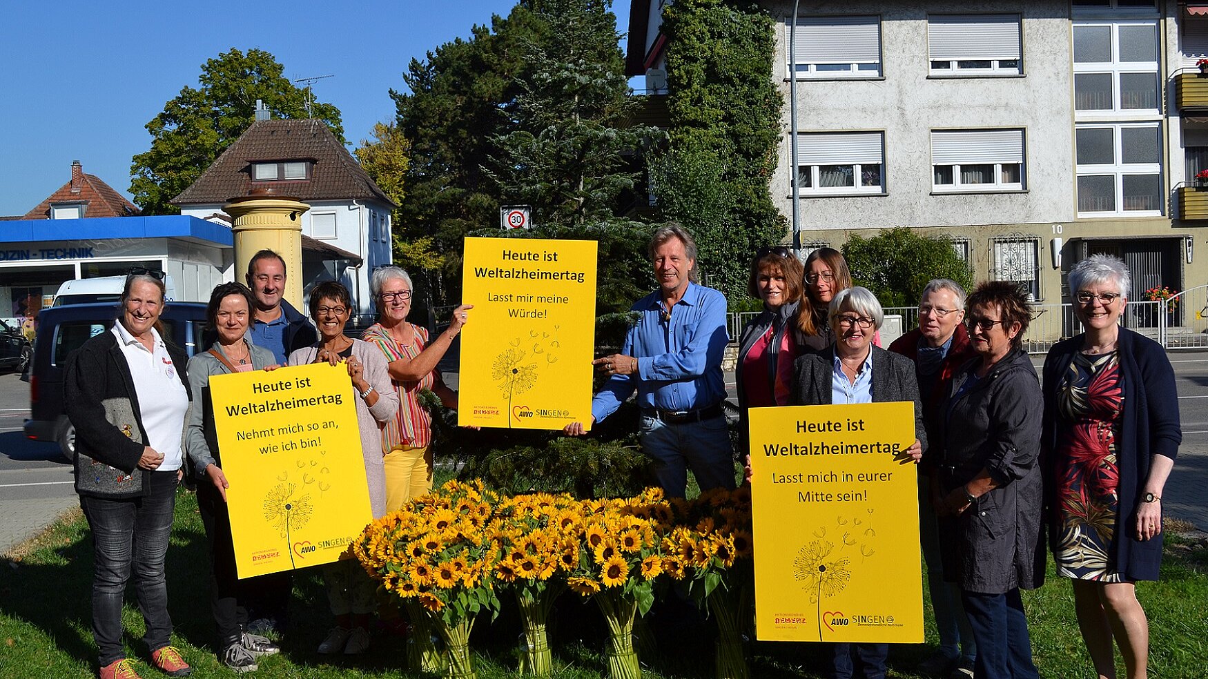 Foto: Zu sehen sind die Mitglieder des Aktionsbündnisses Demenz Singen/Hegau, Vasen mit Sonnenblumen und den gelben Plakaten zum Weltalzheimertag