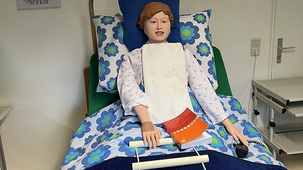 Während der Pandemie wurden einfache Positionierungen an einer Demonstrationspuppe geübt. Hier: An- und Auskleiden Foto: Demonstrationspuppe im Pflegebett