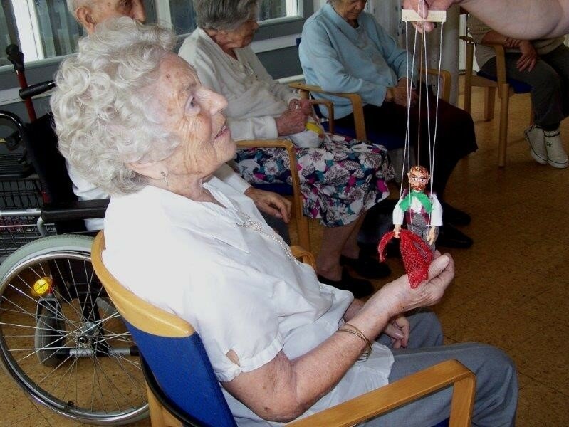 Eine sitzende ältere Dame mit einer Marionette.