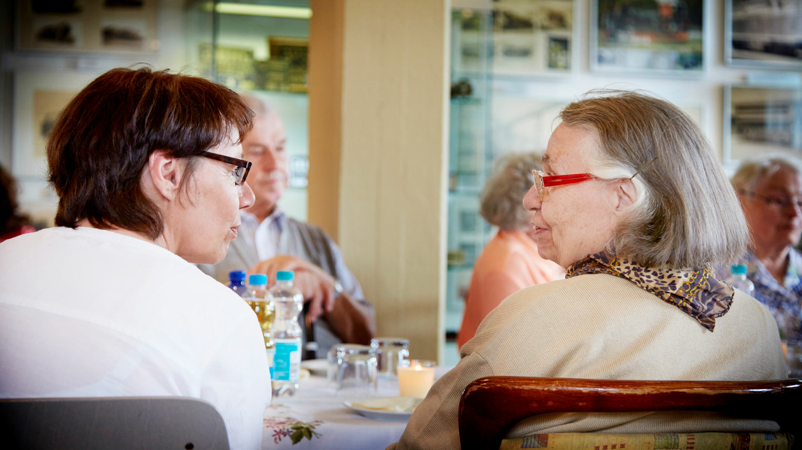 Zwei ältere Damen sitzen am Tisch und unterhalten sich 