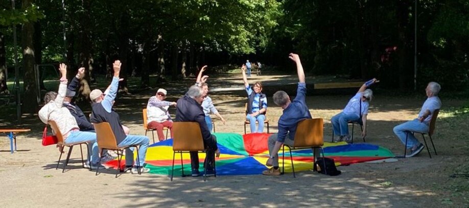 Foto: Senior*innen machen Gymnastik im Sitzen in einem Park