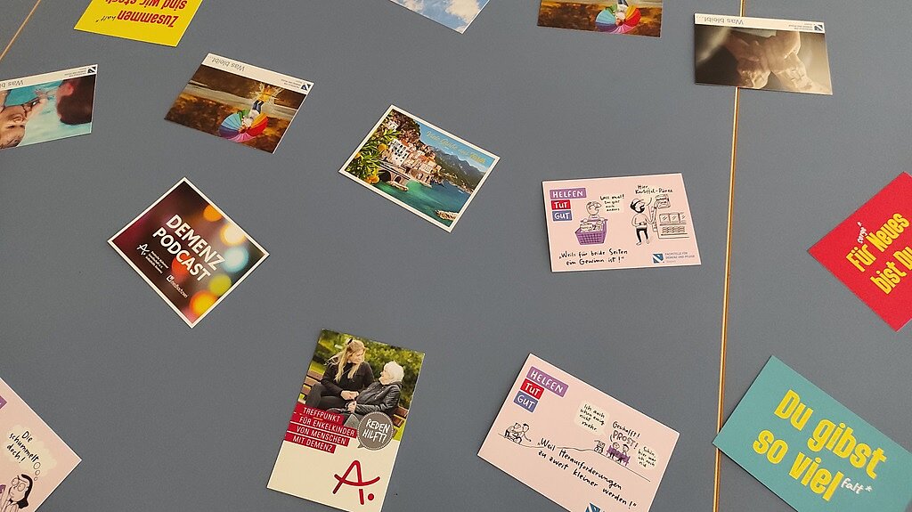 Foto: Auf einem grauen Tisch liegen bunte Postkarten und Flyer.