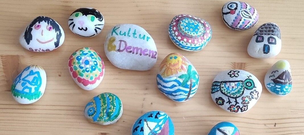 Foto: Vogelperspektive: Bunt bemalte Steine, die auf einem Tisch liegen