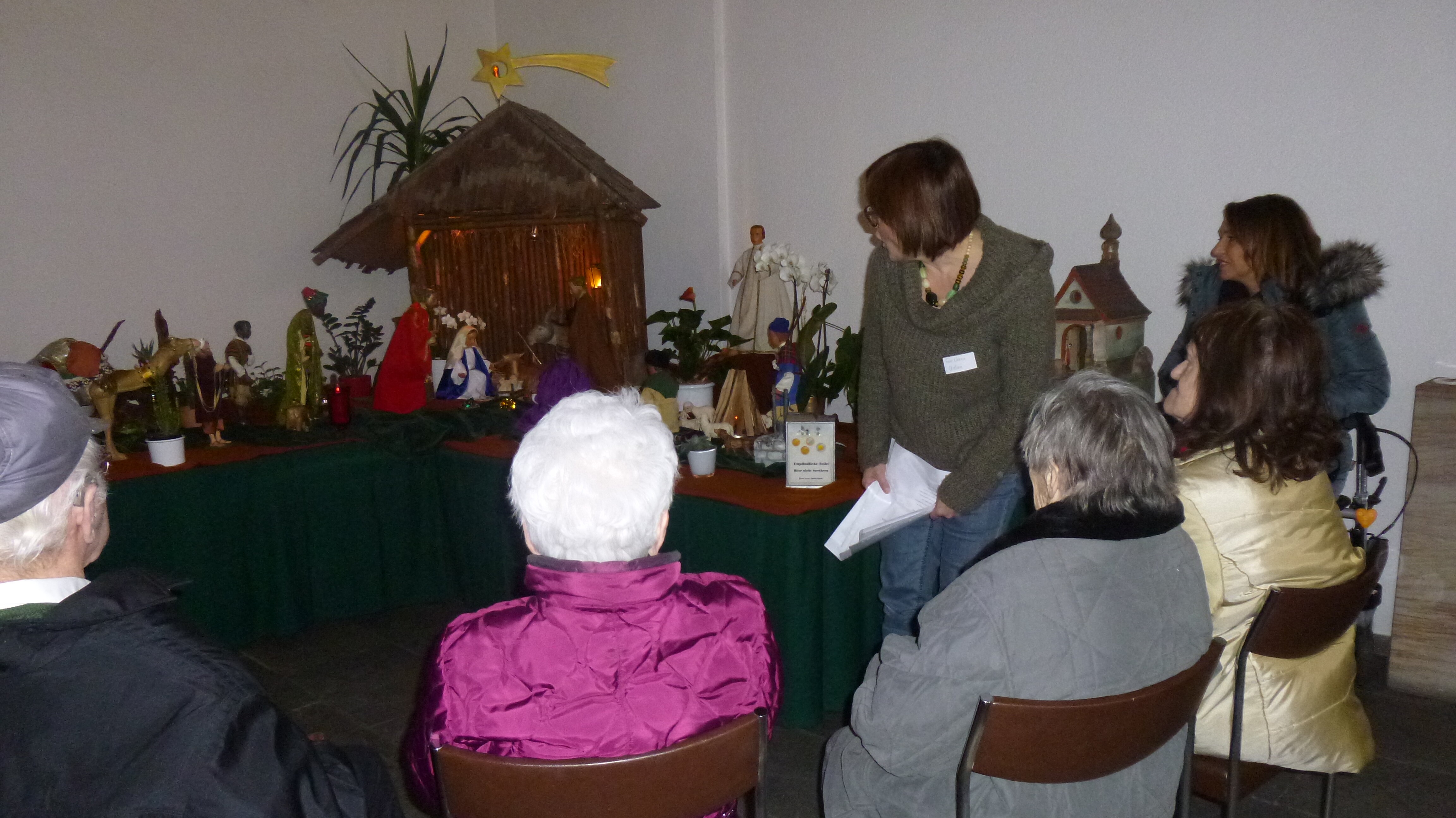 Gemeinsam mit Eva-Maria Urban, Historikerin und ehrenamtliche Mitarbeiterin im Netzwerk „Kultur und Demenz“, betrachten die Gäste die Weihnachtskrippe im Institut Sankt Dominikus Foto: Mehrere Personen betrachten eine Weihnachtskrippe