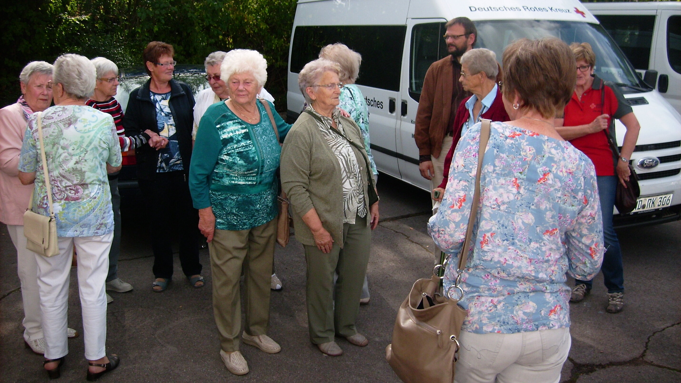 Ausflug mit dem Deutschen Roten Kreuz nach Birkenfeld, 2016 Foto: Eine Gruppe älterer Menschen steht mit der Dorfschwester Annetraud Kling auf einem Parkplatz