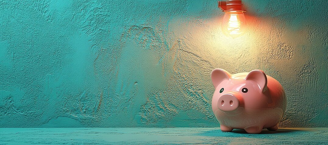 © AdobeStock | SashaMagic Rosa Sparschwein, das von einer Glühlampe angeleuchtet wird