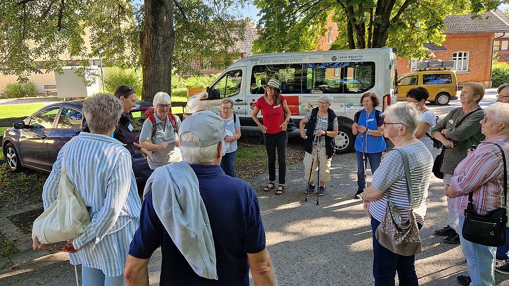 Foto: Eine Seniorengruppe bildet einen Kreis auf einem Parkplatz