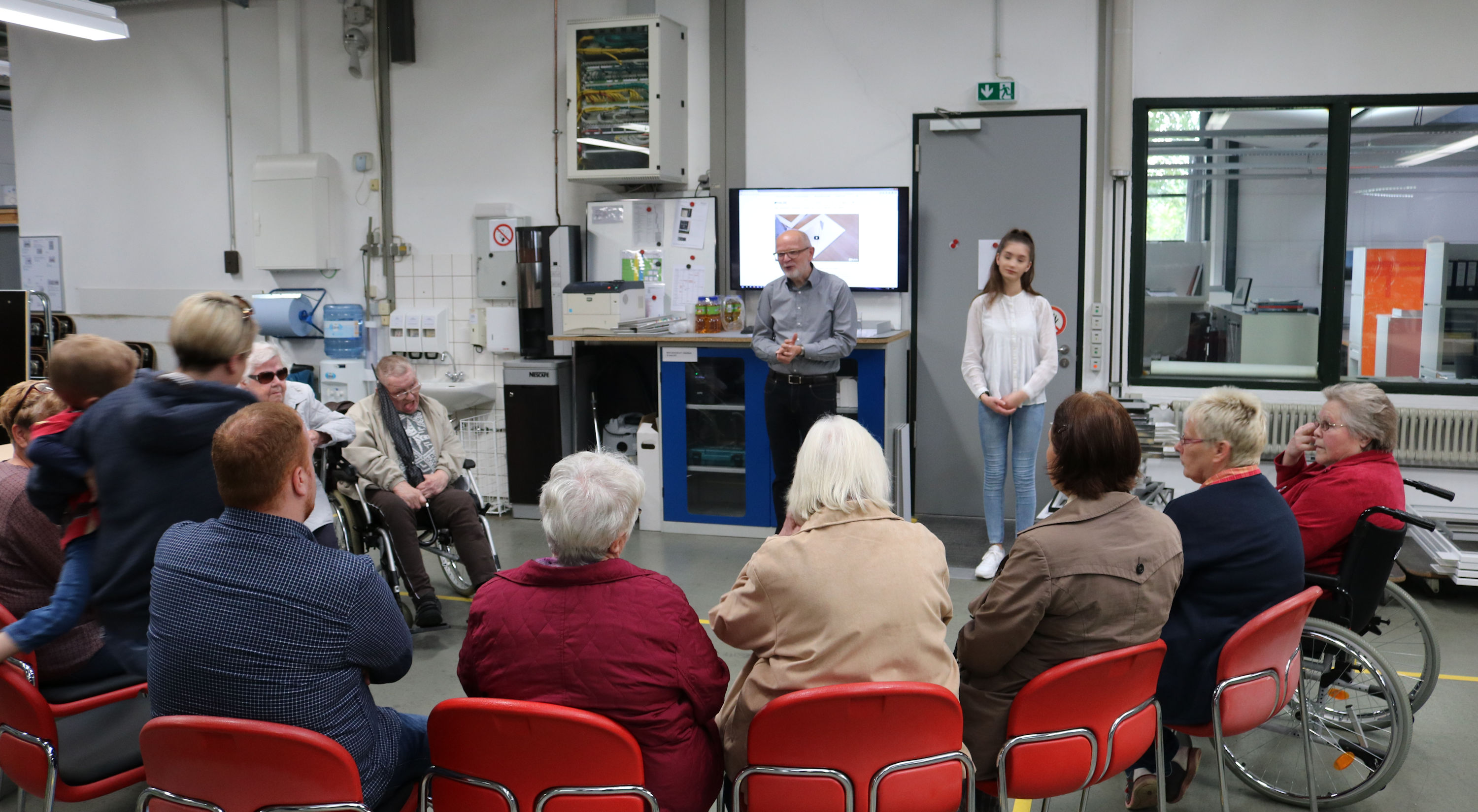 Auf dem Foto sitzen Personen im Halbkreis. Ein Herr spricht zum Publikum
