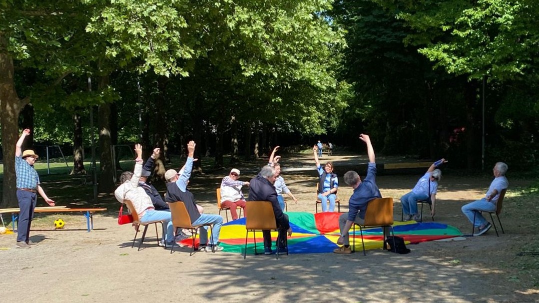 Foto: Senior*innen machen Gymnastik im Sitzen in einem Park
