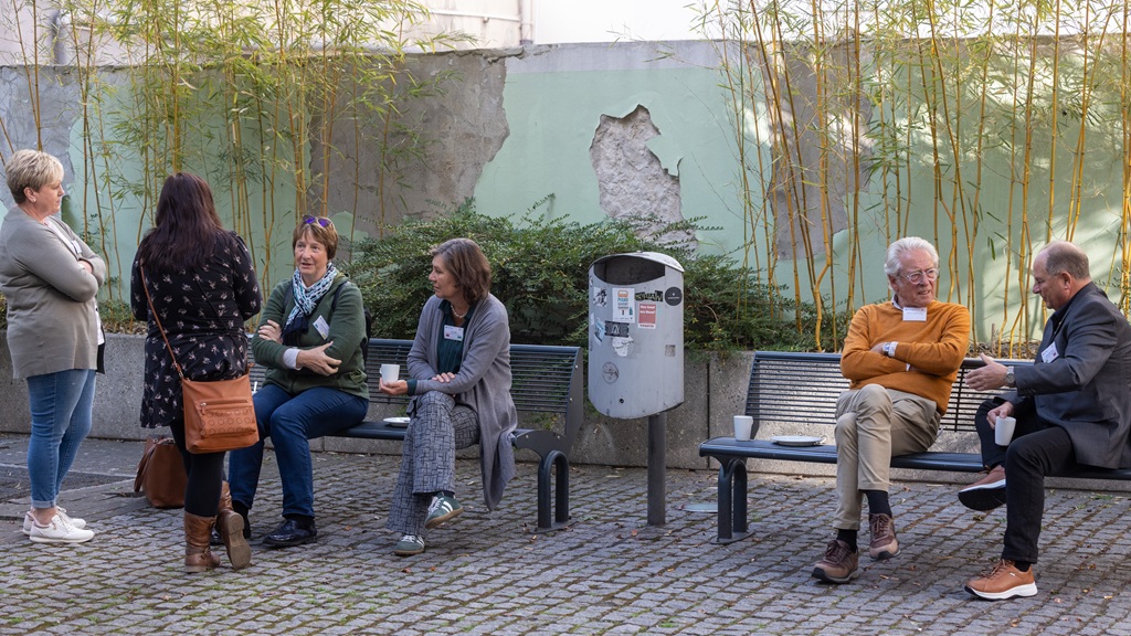 Kaffeepause im Innenhof Foto: Teilnehmende genießen Kaffee und Kuchen in der Pause und sitzen draußen auf den Bänken