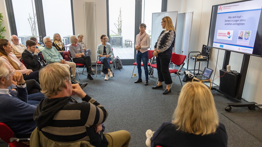 Stefanie Klinowski und Christine Berg mit Teilnehmenden im Workshop "Alles steht Kopf – Demenz in jungen Jahren verstehen und begleiten" Foto: Refierende tragen dem Publikum im Workshop "Demenz in jungen Jahren" etwas vor.