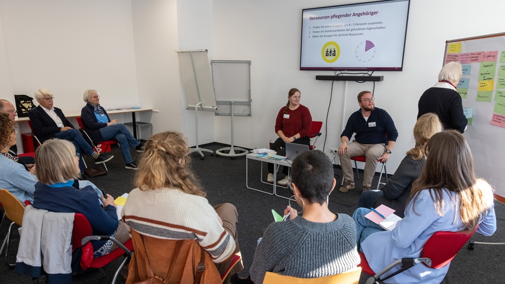 Svenja Evers und Thies Buschke mit Teilnehmenden im Workshop "Pflegende An- und Zugehörige – Manager*innen im Leben und Partner*innen im Netzwerk" Foto: Teilnehmende lauschen den Referierenden im Workshop "Pflegende An- und Zugehörige".